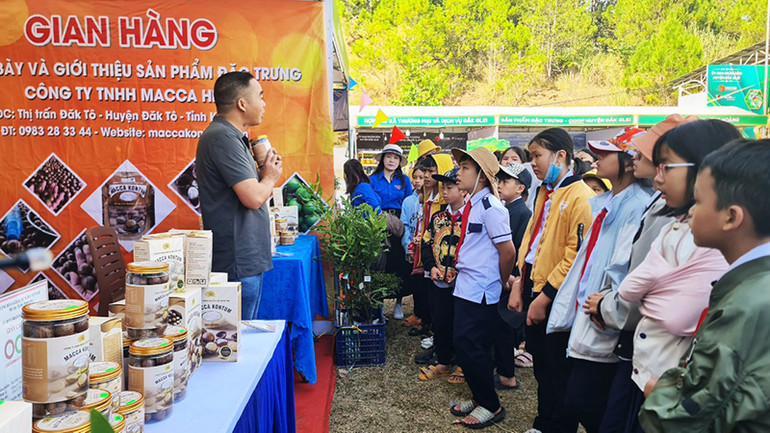 Các em học sinh trường Tiểu học Kim Đồng, xã Đăk Pék, huyện Đăk Glei tham quan, tìm hiểu các sản phẩm làm từ hạt macca.