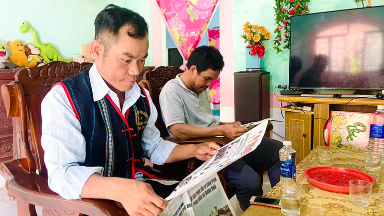 Đồng chí A Thảo (trái) thường xuyên đọc và làm theo báo Đảng để thực hiện hiệu quả công tác tuyên truyền.