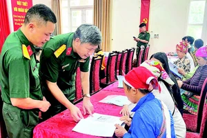 Cán bộ Đoàn Kinh tế-Quốc phòng 345 trao đổi, hướng dẫn người dân kỹ thuật chăn nuôi. (Ảnh QUANG PHẤN)