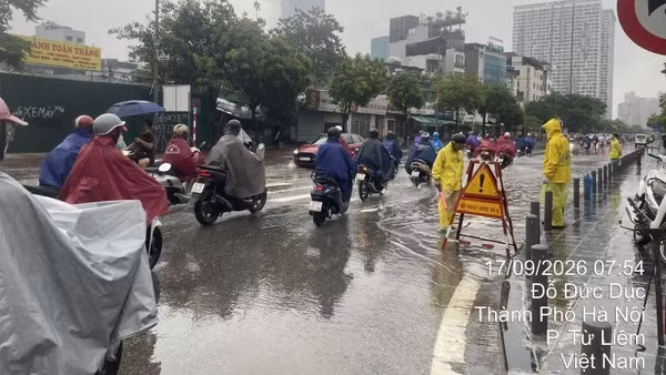 Công nhân thoát nước ứng trực, khơi thông thoát nước sáng 17/9 tại điểm ngập nước trên phố Đỗ Đức Dục, hướng dẫn giao thông cho người dân. (Ảnh: THU THỦY)