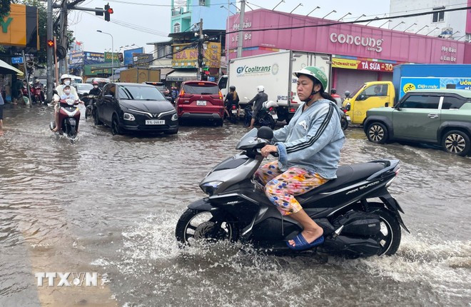 Người dân phường Tân Mỹ, TP Hồ Chí Minh di chuyển khó khăn trong trận triều cường sáng sớm 6/11/2025. (Ảnh: Hương Giang/TTXVN)