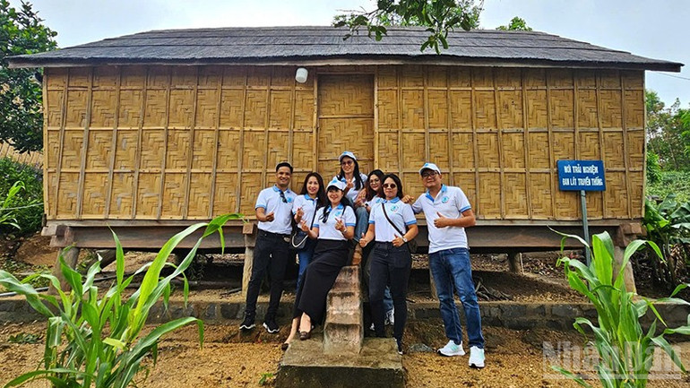 Du khách chụp ảnh lưu niệm với ngôi nhà sàn trên làng kháng chiến Stơr phục dựng. ndo_br_a4.jpg