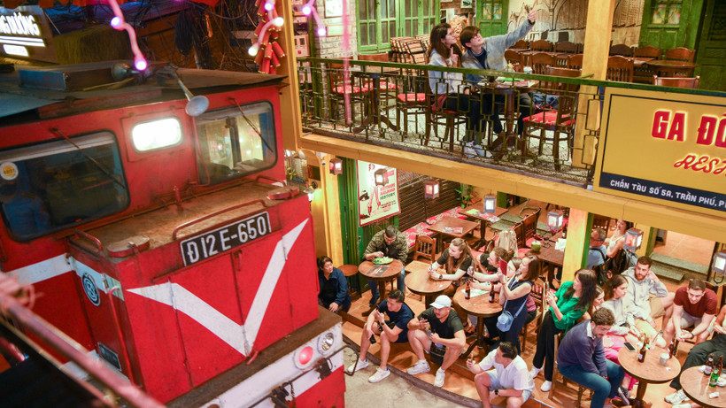 Khách du lịch ngồi sát khu vực đường ray khi tàu đi qua.