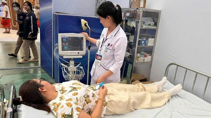 Cán bộ y tế chăm sóc sức khỏe người dân khi tham quan Triển lãm thành tựu đất nước.