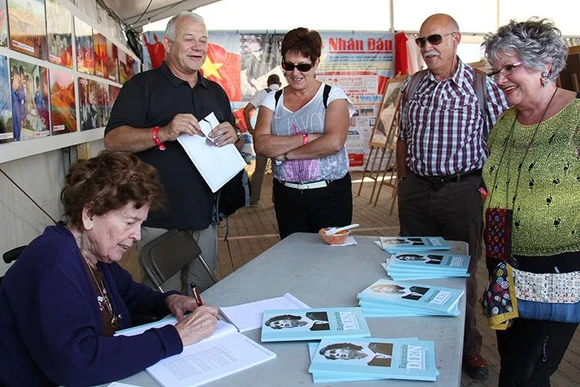Bà Raymonde Dien ký tặng sách tại Hội báo Nhân đạo (Pháp). (Ảnh PHAN VINH) 