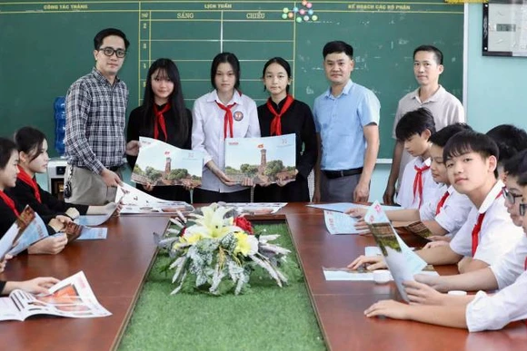 Đại diện Văn phòng Báo Nhân Dân tại Lạng Sơn trao ấn phẩm đặc biệt" Cột cờ Hà Nội" cho giáo viên và học sinh trường Trung học sơ sở thị trấn Bắc Sơn, huyện Bắc Sơn (Lạng Sơn).