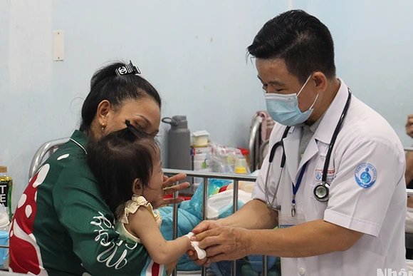 Bác sĩ Bệnh viện Nhi đồng 1 đang khám cho trẻ mắc tay chân miệng (Ảnh: Thế Anh)