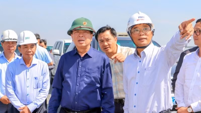 Lãnh đạo Ban Quản lý dự án Mỹ Thuận báo cáo tiến độ dự án cùng với Bộ trưởng Xây dựng Trần Hồng Minh (áo xanh đậm) tại hiện trường.
