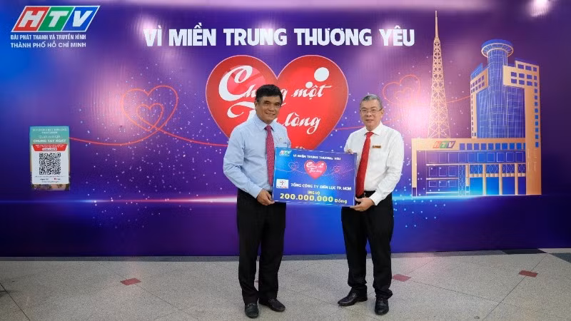 Ông Nguyễn Văn Thanh, Tổng Giám đốc EVNHCMC (áo trắng) trao bảng tượng trưng số tiền 200 triệu ủng hộ Quỹ “Chung một tấm lòng: Vì miền trung thương yêu”.