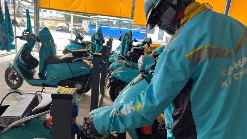 Các lái xe công nghệ bằng xe điện hai bánh sạc pin tại một cơ sở cung cấp dịch vụ sạc pin. 