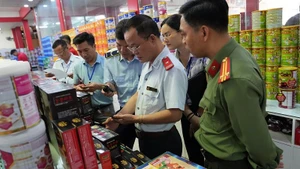 Lực lượng chức năng phối hợp kiểm tra hàng hóa là thực phẩm, sữa, thuốc tại các quầy hàng trung tâm thành phố Điện Biên Phủ. 