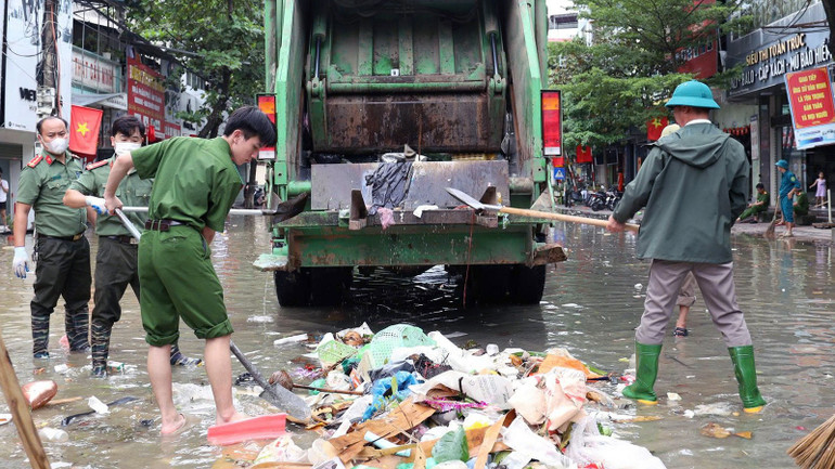 Lực lượng công an và người dân phường Minh Xuân dọn dẹp rác sau khi nước rút. cong-an-ho-tro.jpg
