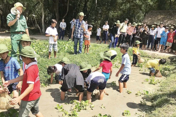 Các em học sinh trải nghiệm hoạt động bắt cá tại Địa đạo Củ Chi. (Ảnh MẠNH HẢO)