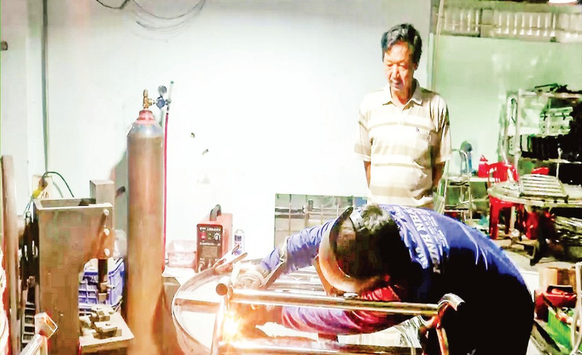 Ông Nguyễn Văn Kiệt quan sát thợ hàn thực hiện công đoạn hoàn thiện sản phẩm.