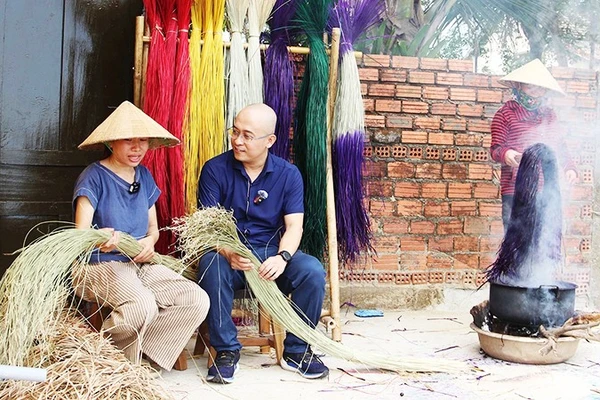 Anh Huy đang trao đổi câu chuyện với chị Phạm Thị Công về nghề dệt chiếu.