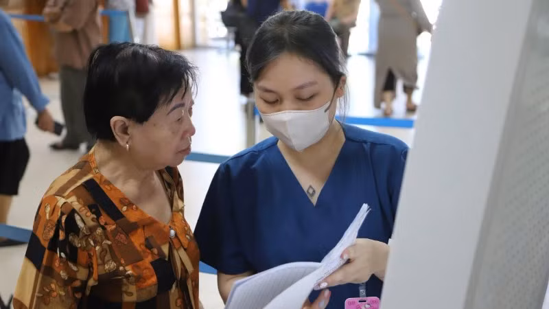 Nhân viên công tác xã hội hướng dẫn bệnh nhân làm thủ tục khám bệnh.