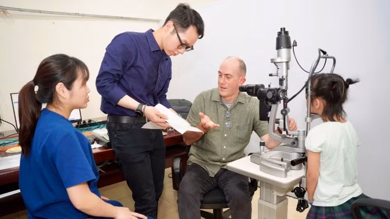 Tiến sĩ Timothy Robert Fricke,Giám đốc Nghiên cứu và Giáo dục tại Viện Nghiên cứu Thị giác Quốc gia, Trường Cao đẳng Khúc xạ Nhãn khoa Úc, đồng thời là Giáo sư danh dự Đại học Y Hà Nội khám cho em nhỏ.