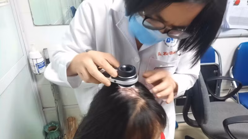 Bác sĩ kiểm tra tình trạng rụng tóc của bệnh nhân.