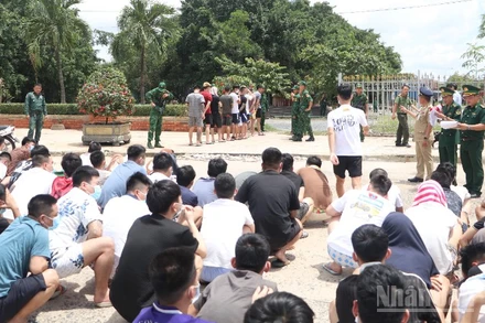 Lực lượng chức năng Việt Nam tiếp nhận các công dân liên quan tội phạm lừa đảo trực tuyến do phía Campuchia bàn giao tại khu vực cửa khẩu Mộc Bài. (Ảnh: ĐINH TRƯỜNG)