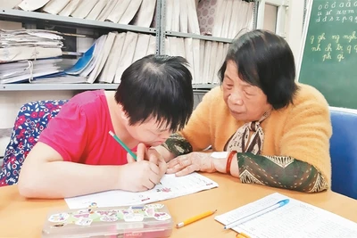 Bà giáo Nguyễn Thị Côi hướng dẫn học sinh lớp học tình thương tập viết. 