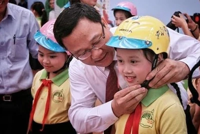 Đồng chí Khuất Việt Hùng, Phó Chủ tịch chuyên trách Ủy ban ATGT quốc gia đội mũ bảo hiểm cho trẻ em. (Ảnh: Ủy ban ATGT quốc gia)