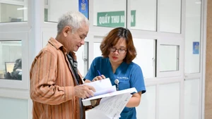 Bác sĩ Bệnh viện Thanh Nhàn, Hà Nội hướng dẫn bệnh nhân đến các phòng chuyên môn. (Ảnh THẾ ĐẠI)