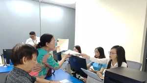 Điểm phục vụ hành chính công xã Thanh Trì (Hà Nội) hướng dẫn người dân làm thủ tục mua bán bất động sản. (Ảnh VĂN HỌC)