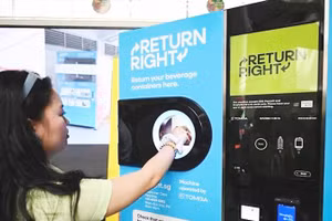 Một người tiêu dùng đặt chai nhựa rỗng vào máy thu gom. Ảnh: CNA