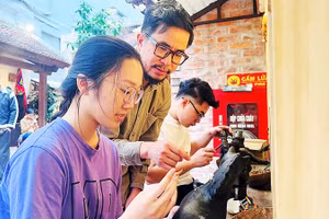 Họa sĩ Nguyễn Tấn Phát hướng dẫn các bạn trẻ thực hành với sơn mài tại đình Hà Vĩ.