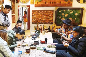 Du khách trải nghiệm làm sơn mài tại làng nghề Hạ Thái (Hà Nội).