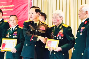 Thượng tướng Khamliang Outhakaysone - Bộ trưởng Quốc phòng Lào chụp ảnh lưu niệm cùng Trung tá Nguyễn Cao Phong và các bộ đội tình nguyện tại Lào. Ảnh: NVCC