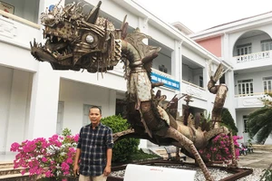 Họa sĩ Đinh Thanh Hải bên tác phẩm “Con rồng sắt” của nhà điêu khắc Pháp Marc Morvan, làm bằng phế liệu vỏ bom đạn, inox sau chiến tranh, hiện đặt tại sân Trường đại học Khánh Hòa.