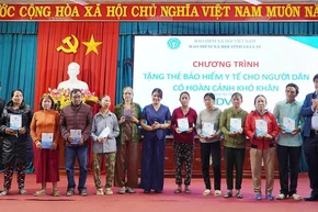 Phó Giám đốc Bảo hiểm xã hội tỉnh Trần Ngọc Tuấn cùng các đại biểu trao tặng thẻ bảo hiểm y tế cho người dân. (Ảnh: BTC)