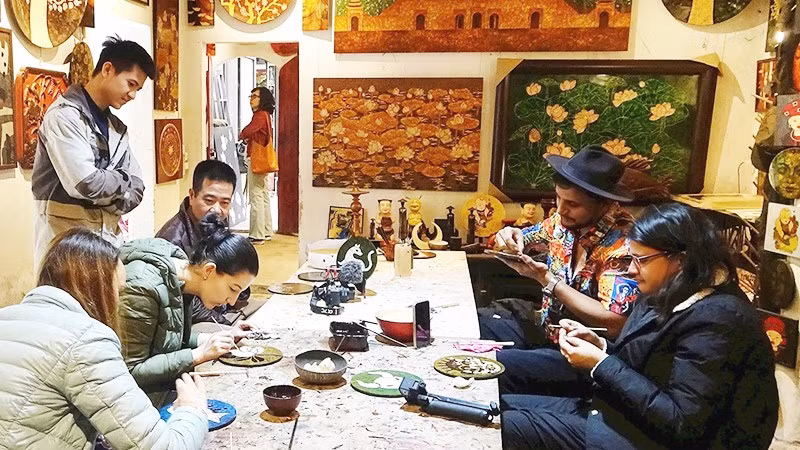 Du khách trải nghiệm làm sơn mài tại làng nghề Hạ Thái (Hà Nội).