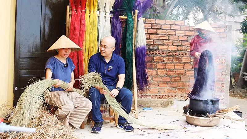 Anh Huy đang trao đổi câu chuyện với chị Phạm Thị Công về nghề dệt chiếu.