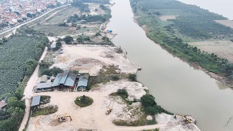 Cụm bến bãi tập kết cát nằm sâu trong một nhánh sông Hồng thuộc Công ty Cổ phần Thương binh Thành Luân, tách biệt khu dân cư, các mố cầu cảng được đắp dựng vươn ra sông để phục vụ việc vận chuyển cát từ dưới sông lên bãi. Ảnh chụp ngày 28/12/2025.