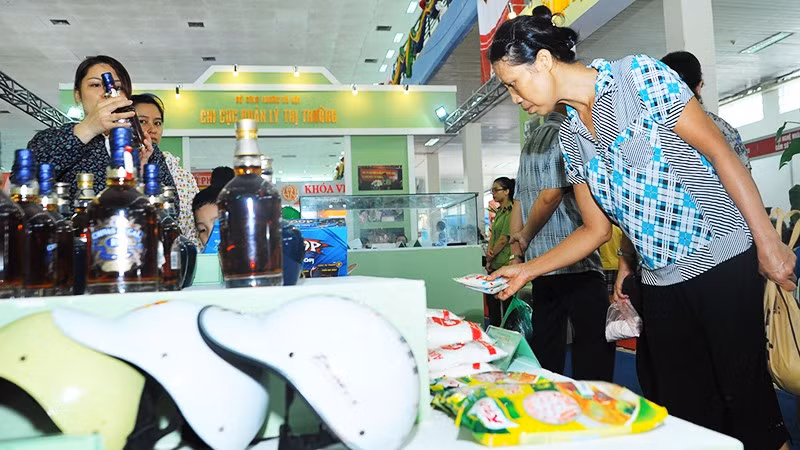 Người tiêu dùng xem các sản phẩm hàng nhái được quản lý thị trường trưng bày. Ảnh: NAM ANH