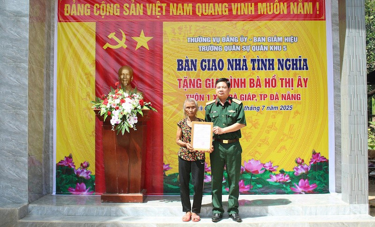 Đại tá Đặng Văn Trụ - Chính ủy Nhà trường trao quyết định tặng nhà bà Hồ Thị Ây. (Ảnh: ĐÌNH TĂNG) ndo_br_qku5.jpg