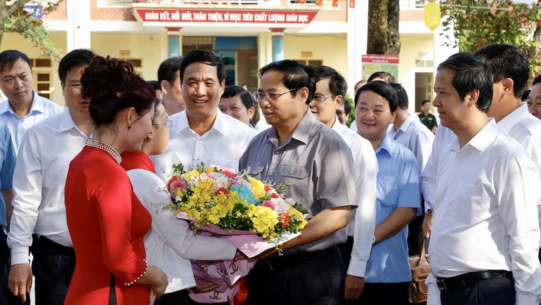 Thầy cô giáo và học sinh Trường tiểu học thị trấn Yên Lập chào đón và tặng hoa cho Thủ tướng.