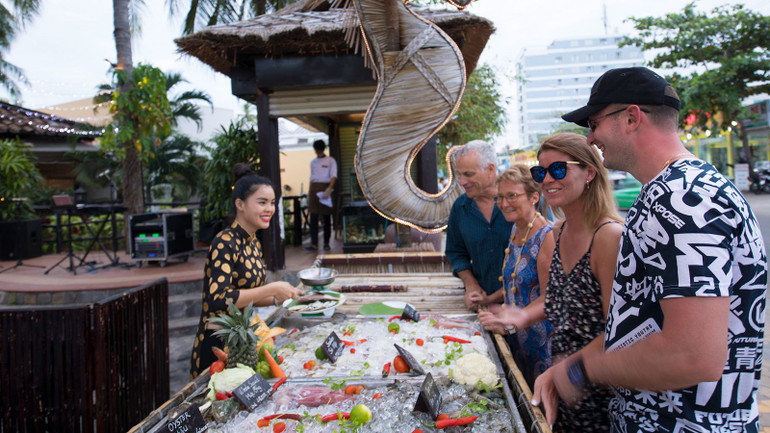 Du khách nước ngoài thưởng thức hải sản tại khu nghỉ dưỡng.