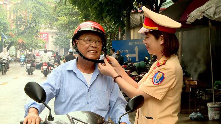 Cảnh sát giao thông phát mũ bảo hiểm tặng người dân. (Ảnh HOÀNG DUY)