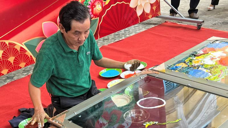 Họa sĩ Đoàn Việt Tiến biểu diễn vẽ tranh ngược trên kính.