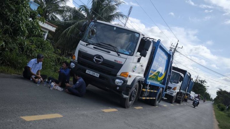 Xe chở rác xếp hàng chờ bên ngoài bãi rác An Hiệp. (Ảnh: HOÀNG TRUNG)
