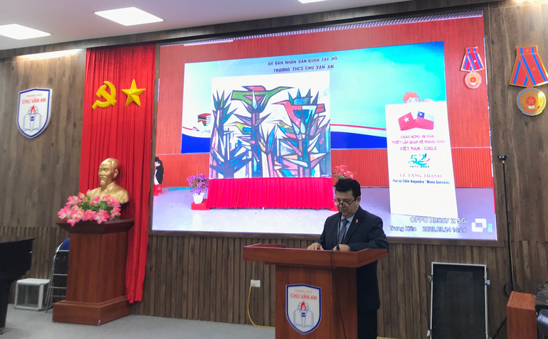 Ngài Sergio Narea, Đại sứ đặc mệnh toàn quyền Đại sứ quán Chile tại Việt Nam phát biểu. Trên màn chiếu đằng sau là hình ảnh bức tranh được trao tặng cho nhà trường.