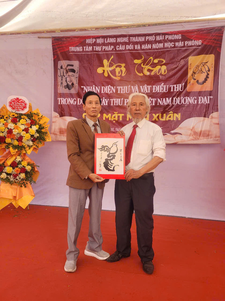 Nhà thư pháp Lê Thiên Lý (phải) tặng bức thư pháp viết theo lối “Vật điểu thư”.