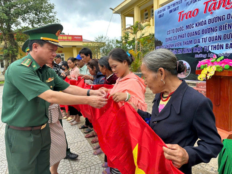 Trao tặng cờ Tổ quốc, móc khóa đường dây nóng cho bà con.
