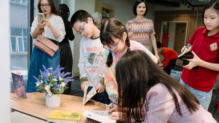 Nhà văn ký tặng sách cho bạn đọc nhỏ tuổi.