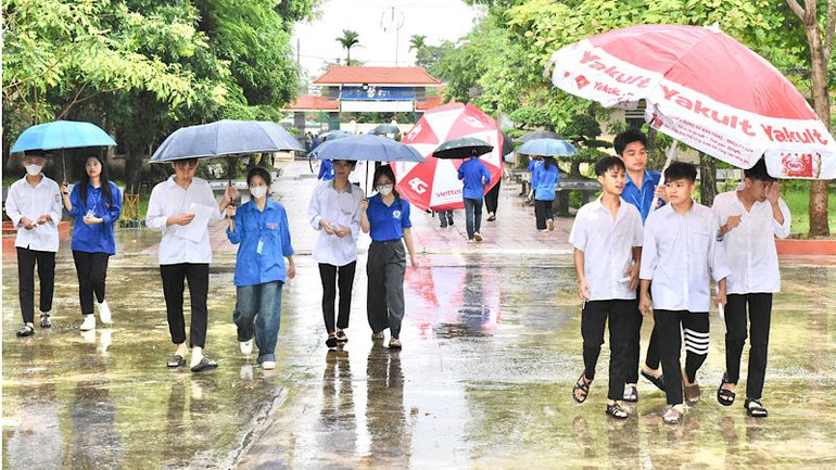 Lực lượng thanh niên tình nguyện giúp thí sinh vào địa điểm thi trong điều kiện trời mưa nặng hạt sáng 27/6.