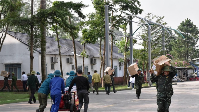 Các lực lượng phối hợp di chuyển hàng hóa khỏi khu vực cháy. (Ảnh: XUÂN TRƯỜNG)