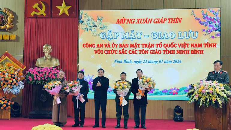 Đồng chí Đoàn Minh Huấn, Ủy viên Trung ương Đảng, Bí thư Tỉnh ủy Ninh Bình tặng hoa, chúc mừng đại diện các tổ chức tôn giáo và lãnh đạo Công an tỉnh, Ủy ban Mặt trận Tổ quốc tỉnh Ninh Bình. Ảnh: XUÂN TRƯỜNG